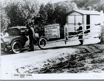 Car with driver paying toll at tollgate  with sign showing fees 1929