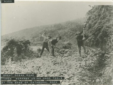 Three workers using hand tools on Great Ocean Road at base of Cathedral Rock