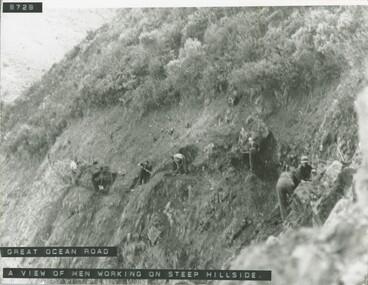 Men working with hand tools on steep hillside on Great Ocean road