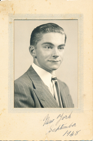 A black and white portrait photograph, mounted on a cream cardboard frame, of Allan Quinn as a young man. At the bottom written in ink: New York, September 1948.