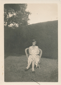  Lillie Duncan  sitting on a cane chair in a garden