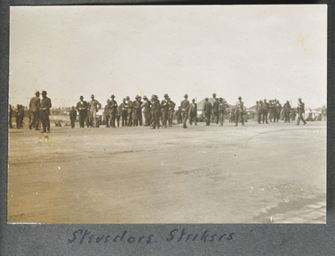 Small sepia photograph in album depicting a group of men (stevedores)