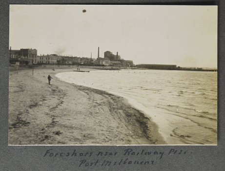 Small sepia photograph depicting the Beach of Port Melbourne. In the baclground we can see the sitar works.