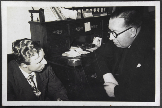 Photograph of a chaplain at his desk talking to a young seaman.seated next to him.