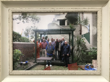 Group of volunteers under the pergola in the garden of the Mission to Seafarers, Melbourne.