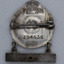 Back of small silver badge with hanging bar, showing maker and issue number