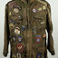 Long sleeve, mid-length, front-zip fastening khaki jacket, adorned with many cloth and metal badges relating to parachuting.
