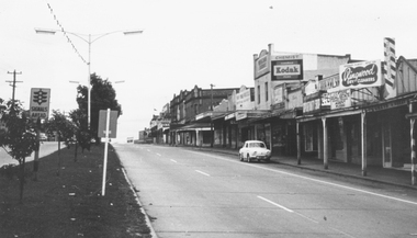 Photograph, Maroondah Highway, Ringwood, looking west from Warrandyte Road - 1965. (Flag at half-mast on town hall and lack of traffic indicates possibly ANZAC Day public holiday.)