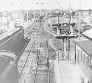 Photograph, Ringwood railway station precinct.  Post number 35 in view from the foot bridge.  The signalman is giving the staff to the driver of a dog box suburban train, from Bayswater