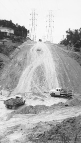 Photograph, Trucks at base of steep hill with power pylons at top. Glenvale or Timbertop  (Undated)