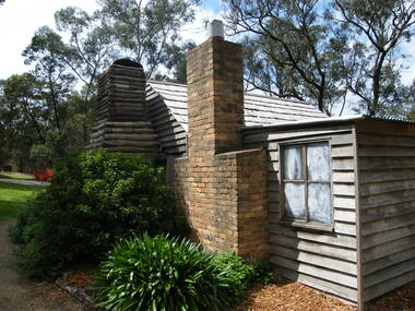 Photograph, Showing the exterior views of the facsimile of the miner's hut, located at the back of Ringwood Lake, from the original that once stood on Maroondah Highway in the 1870s onwards. The cottage was erected by the Ringwood City Council in conjunction with Ringwood Historical Research Group (now Ringwood & District Historical Society). Officially opened by Mayor Cr Pat Gotlib JP on 29th May 1983