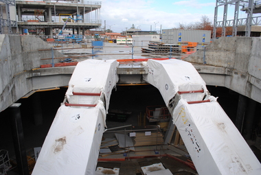 Photograph, Probuild tour of Stage 5 building of Eastland, Ringwood in 2015. Showing new escalators at entrance to new Eastland. The REALM library being built on left. Railway Station and offices in background