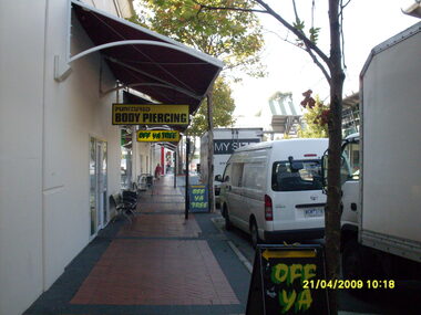 Photograph, Access road in front of Eastland looking east. Showing "Off Ya Tree" and "Punctured Body Piercing" shops. Ringwood on 21 April 2009