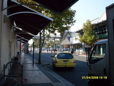 Photograph, Eastland access road looking east, on 21 April 2009. Showing cab and shops on south side of Eastland
