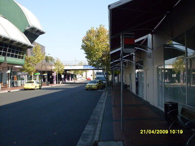 Photograph, Eastland access road looking west, on 21 April 2009. Showing library on left, shops on right and car overpass
