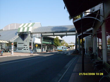 Photograph, Eastland access road looking west, on 21 April 2009. Showing library on left, shops on right and car overpass. Also Ventura buses and pedestrian crossing to Eastland