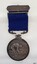 Silver bar with inscription, attached to blue ribbon with silver medal hanging rom it