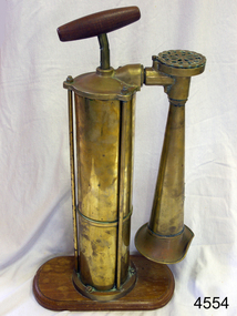 Shiny brass foghorn with wooden handle and stand.