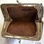 Purse's metal frame is joined to the leather fabric, with edges of leather visible