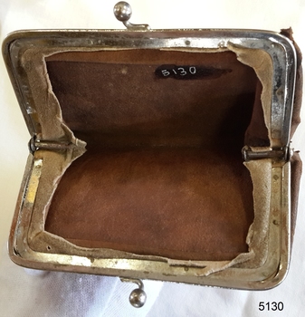 Purse's metal frame is joined to the leather fabric, with edges of leather visible