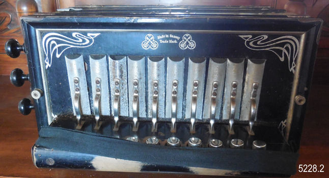 The silver decoration is painted around the accordion's keyboard, which has white and black keys