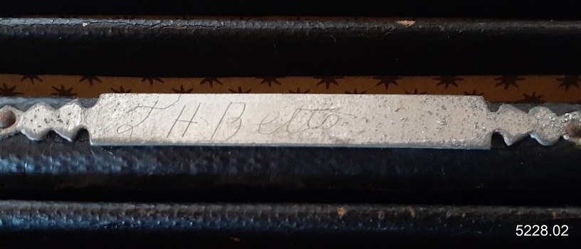 Handwritten identification etched into the accordion's surface on the metal trimming
