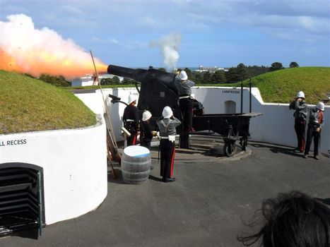 Men in uniform gather around a cannon that has just been fired