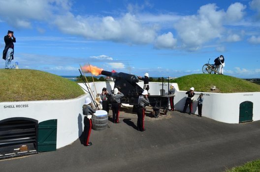 Men in uniform around a cannon as it is fired
