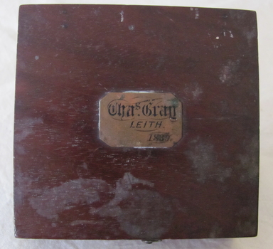Rectangular brass plaque attached to compass with inscription
