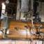 Cylindrical horizontal boiler with varnished timber encasing and shiny copper pipes