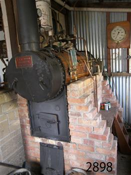 Front of boiler has a red plaque. The boiler is mounted above a brick structure
