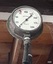 Pressure gauge has a white face and black markings and needle. A red marker is attached to the dial