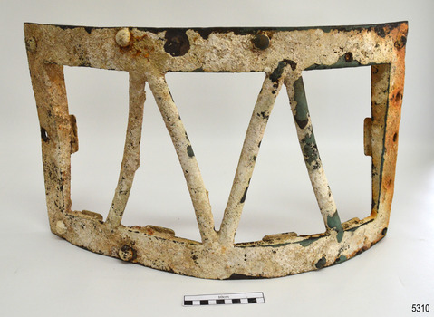 Metal frame is headily encrusted. Fixing bolt's heads are visible. Metal rods form 'V' shape.