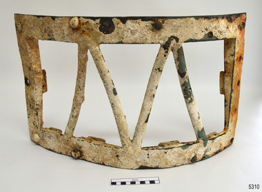 Metal frame is headily encrusted. Fixing bolt's heads are visible. Metal rods form 'V' shape.