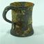 Metal tankard with rolled lip and flared base. Has encrustations.