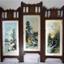 Wooden screen with three hinged panels, each with a coloured print behind glass