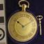 Decorative gold pocket watch with clear glass case and key