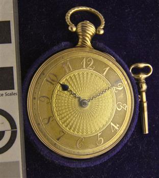 Decorative gold pocket watch with clear glass case and key