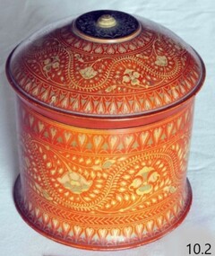 Container is orange coloured and has a lid with a knob. Outside is decorative.