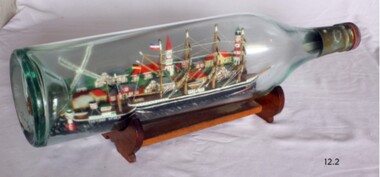 Models of two vessels have been inserted into this clear glass bottle, which is on its own stand.