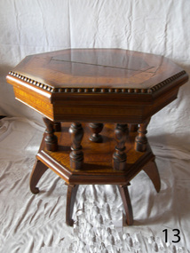 Turned pillars support the table top, which has inlaid pieces of different timbers.  one pillar per leg and one pillar in the centre.