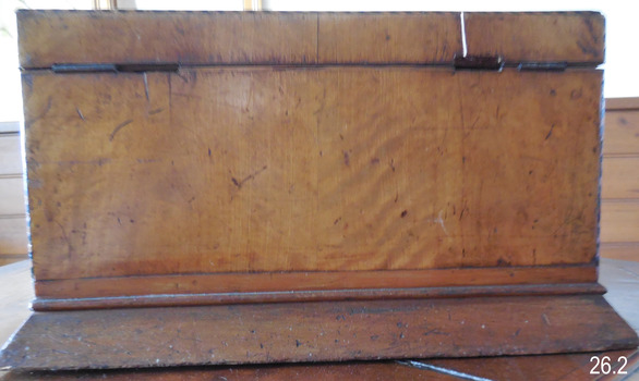 The back is plain, showing metal hinges for the lid. 