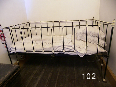 Iron cot has black ironwork, with white paint on the joints