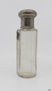 Clear glass bottle with ten sides. Bottle has a round metal lid.