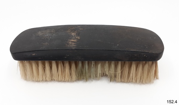 Brush has brown shaped handle grip and yellow bristles.