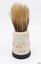 Yellow-bristled brush has round black base, and round white body. Bristles are worn.