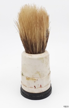 Yellow-bristled brush has round black base, and round white body. Bristles are worn.