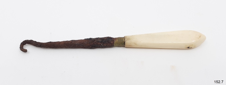 Button hook is joined to brass collar attached to a white, handle that has a rounded end