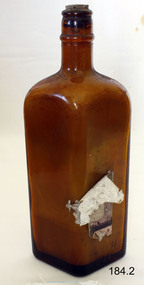 A brown glassfour sided bottle with cork. 