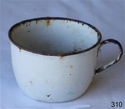 A white round enamel cup or mug with handle. Partly rusty.